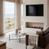 Modern living room with a fireplace, television, and large windows overlooking a scenic view.